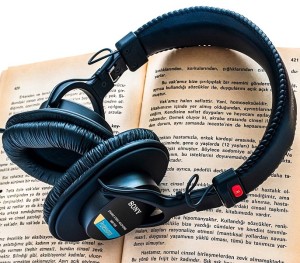 Kopfhörer auf einem Buch: Hörbücher besser für Kinder als Videos (Foto: pixelio.com, Ri_Ya)